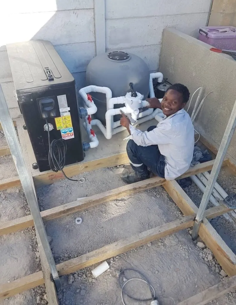 Ishmael Nkhata, founder of Mother City Pools, installing a heat pump and sand filter