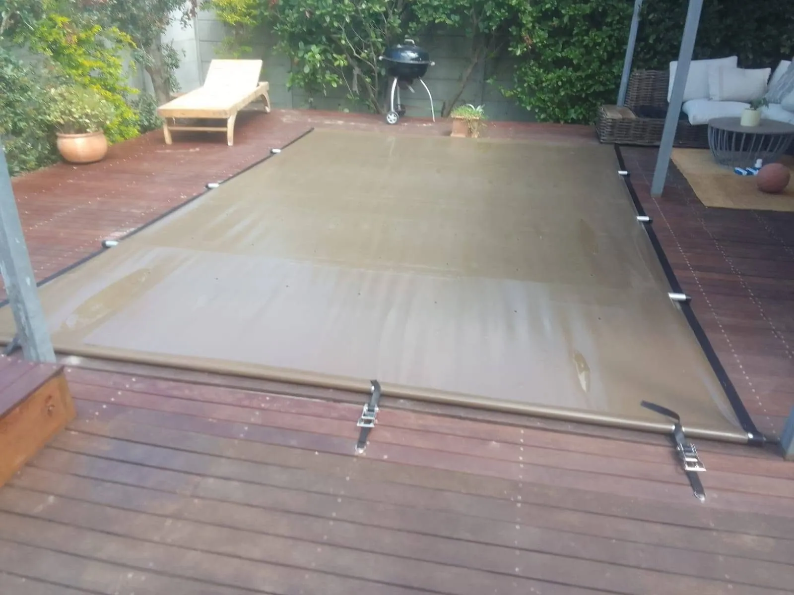 PVC ratchet pool cover fitted over a pool on a timber deck
